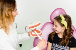 Dentist with little girl, talking about dental hygiene